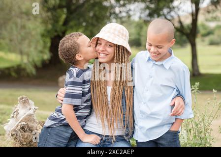Brother kissing sister on the cheek while hugging each other Stock Photo