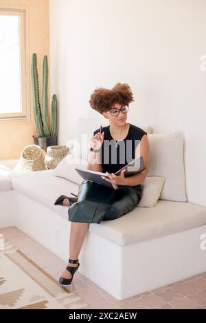 Women wearing glasses sitting on couch with a notebook and pen Stock Photo