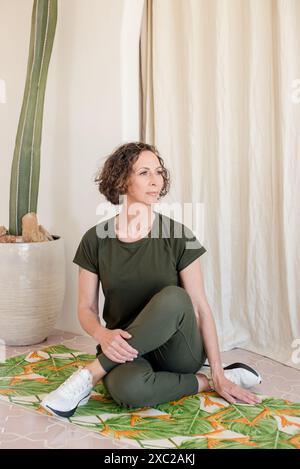 Women practicing yoga sitting down in front of cactus Stock Photo