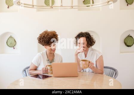 Two women working on laptop laughing Stock Photo