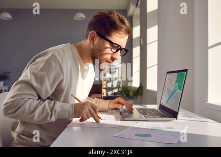 Professional cartographer working with printed cadastral map at table on his workplace. Stock Photo