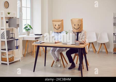 Colleagues Working Together With Paper Bags On Heads Depicting Positive Emotions Stock Photo