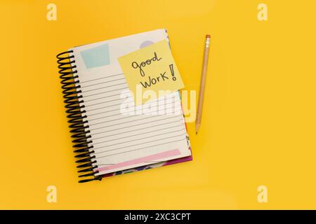 Good work short phrase written on a yellow sticky paper on a note pad on a yellow background Stock Photo