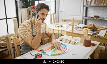 Handsome hispanic man on phone choosing colors in a sunny carpentry workshop Stock Photo