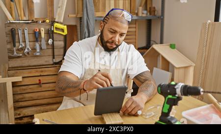 Handsome bearded man using tablet in a well-equipped carpentry workshop Stock Photo