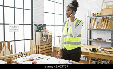 African american woman carpenter using phone in a workshop. Stock Photo