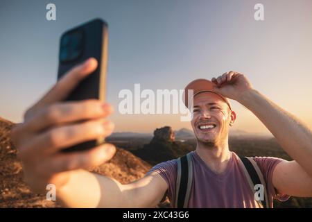 Happy man taking selfie photo from summer vacation day. Handsome tourist wearing cap and smiling at camera against tropical landscape with Sigiriya ro Stock Photo