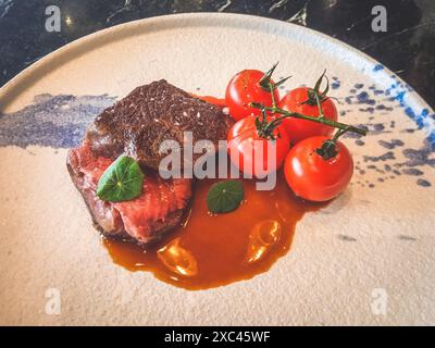 Wagyu Tri-tip made from 2GR Wagyu Tri-tip, red wine jus, baby tomatoes on vine Stock Photo
