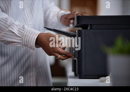 Side view close up on printer and female hands of office worker pressing button on multifunction laser printer in home office or at workplace. Student scanning documents at university, copy space Stock Photo