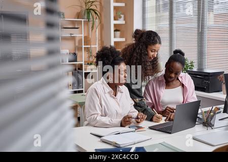 Diverse team of businesswomen collaborating writing notes on paper and discussion issues in office, copy space Stock Photo