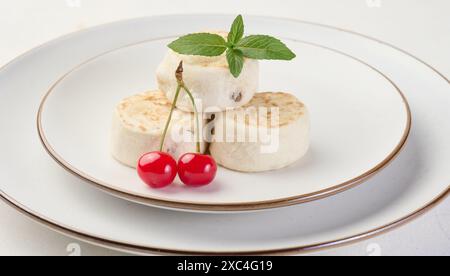 Round small fried cheesecakes on a plate with blueberries. Background white Stock Photo