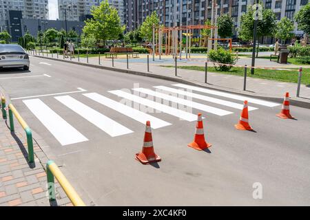 Applying road markings. Pedestrian crossing on the street in the yard. Cones Stock Photo