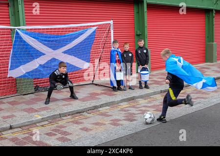 Glasgow, UK. 14th June, 2024. As Scotland prepares tp play Germany in the opening match of the euro 2024 competition, Glasgow is in the grip of football fever . Street stalls selling flags, hats and scarves are about the city centre and young boys from Glasgow Vale 2015/2017 football club indulge in some street football while collecting funds for their team. Credit: Findlay/Alamy Live News Stock Photo