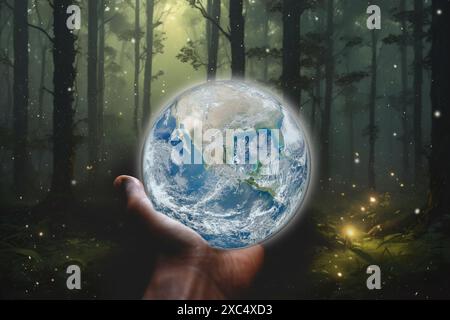 Hand holding glowing crystal Earth brings enchanted forest to life with fireflies background. Elements of this image used with permission from NASA (h Stock Photo