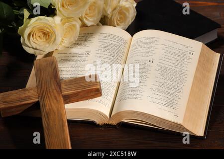 Bibles, cross and roses on wooden table, closeup. Religion of Christianity Stock Photo