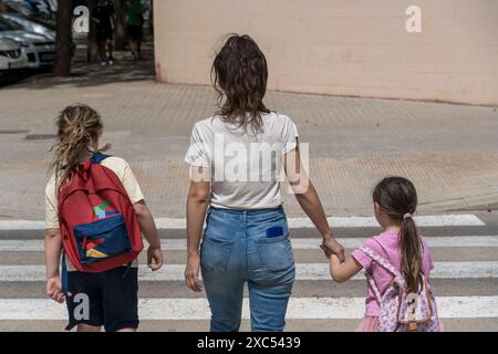 Family walks to school on the first day of school. Sunny day, beginning of the school year, return to school, family with their backs turned, on the w Stock Photo