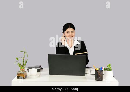 Beautiful Asian Indian Receptinist Entrepreneur with laptop, headphone and diary gives gestures  and expressions Stock Photo