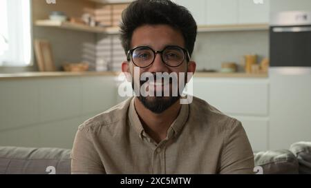 Portrait smiling Arabian Indian muslim middle eastern man happy millennial guy homeowner alone on couch relax on sofa in kitchen male renter own Stock Photo