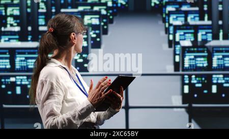 Adept supervisor in high tech location equipped to handle modern computing requirements, doing regular upgrades to server cabinets, increasing processing power and storage capacity to prevent glitches Stock Photo