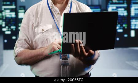 Cloud computing business executive expertly managing data while navigating in industrial server room. Data storage company agent ensuring optimal cybersecurity protection, optimizing systems Stock Photo
