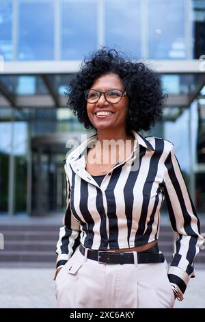 Portrait of African American curly hair business woman cheerful posing for photo standing Stock Photo