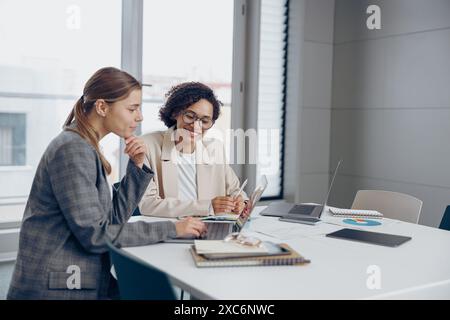 Female sales managers working on project together and use laptop sitting in office Stock Photo