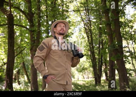 Forester with binoculars examining plants in forest Stock Photo