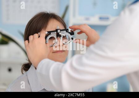 Female ophthalmologist putting trial frame on patient in clinic, closeup Stock Photo