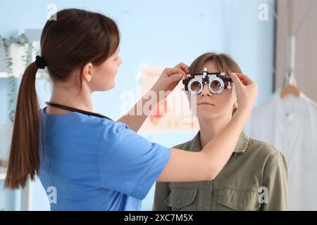 Female ophthalmologist putting trial frame on patient in clinic Stock Photo