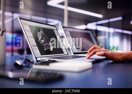African American Female Engineer Developing Mechanical Parts Using 3D CAD Software on Laptop at Factory Office Stock Photo