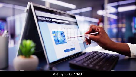 African American Woman Online Shopping for Luxury Clothes on Laptop Screen: Digital Marketing Professional at Ecommerce Boutique Store. Stock Photo