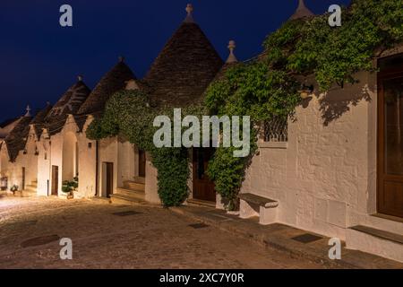 Famous historic old dry stone trulli houses with conical roofs in Alberobello, Italy. Night view Stock Photo