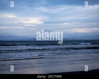 Mt. Fuji in the distance across the waves of Sagami Bay in the evening twilight. Stock Photo