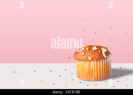 Almond muffin with confetti isolated white table on pink background Stock Photo