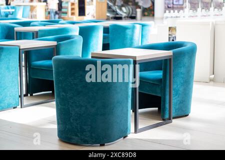 A row of blue chairs and tables arranged neatly in a room, with a serene and calming ambiance Stock Photo