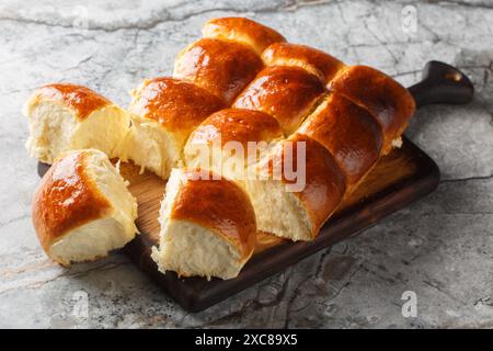 Homemade Freshly baked soft Dinner Rolls or Hawaiian Buns closeup on the wooden board on the table. Horizontal Stock Photo