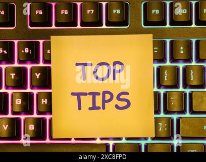 Business concept. Text TOP TIPS on a yellow sticker lying on the keyboard with a colored backlight Stock Photo