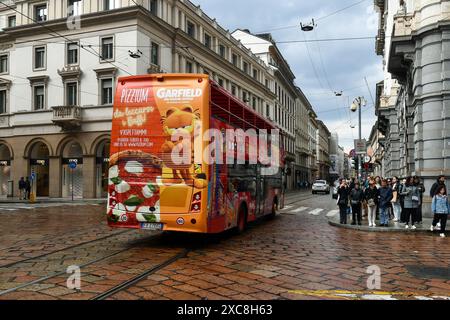 A colorful city sightseeing bus passing in Via Alessandro Manzoni in the city centre of Milan, Lombardy, Italy Stock Photo