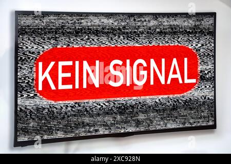 Germany - June 15, 2024: TV on the wall, with a noisy and crackly picture or screen. The following message appears in the center: NO SIGNAL. Symbol for reception interference on the TV set. PHOTOMONTAGE *** Fernseher an der Wand, mit rauschendem und krisseligem Bild bzw. Bildschirm. In der Mitte erscheint die Meldung: KEIN SIGNAL. Symbol für Empfangsstörung beim TV-Gerät. FOTOMONTAGE Stock Photo