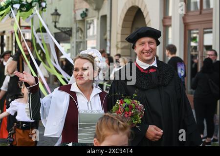 Lutherstadt Wittenberg, Germany. 15th June, 2024. The bridal couple Martin Luther and Katharina von Bora, portrayed by Carolin and Oliver Koschmieder, wave to the spectators at the edge of the procession. The Wittenberg festival 'Luther's Wedding' is taking place this weekend. On June 13, 1525, the former monk Martin Luther and the escaped nun Katharina von Bora married in Wittenberg. Credit: Heiko Rebsch/dpa/Alamy Live News Stock Photo