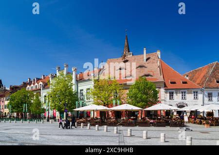 Sibiu, Transylvania, Romania - May 2, 2022: Piata Mica or The Small Square, historical center of Sibiu. The Eyes of Sibiu - iconic eyebrow dormers on roofs of Sibiu's houses. Bright sunny day. Stock Photo