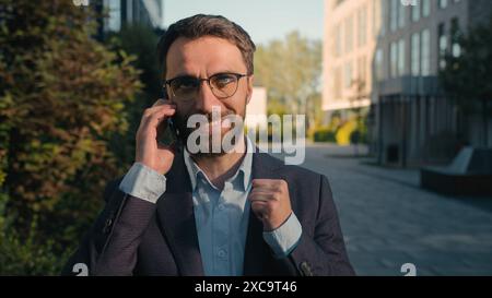 Caucasian businessman successful business entrepreneur commercial ceo employer chief walking on street talking mobile phone on way to work male busy Stock Photo
