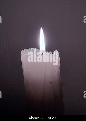 burning thick white candle on a plain gray background Stock Photo