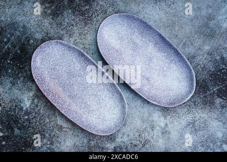 Pair of empty blue oblong plates on gray concrete background. Top view, with copy space Stock Photo