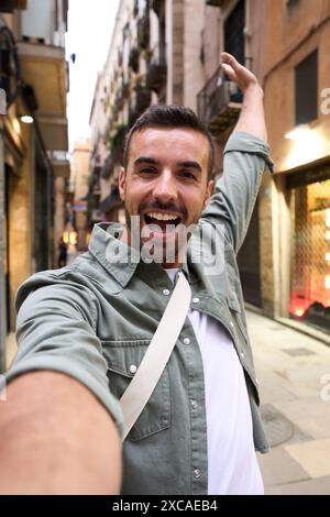 Young excited Caucasian man taking selfie on Paris touristic city street in background.  Stock Photo