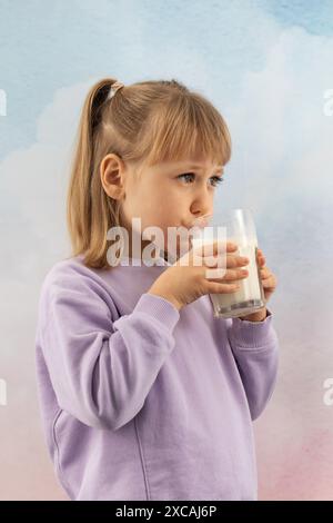 Blonde girl holds glass in hands drinking milk before sleep Stock Photo