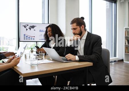 Diverse team in a focused business meeting with technology Stock Photo