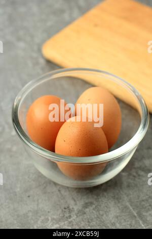 Three Eggs on Glass Bowl, Above Grey Table Background Stock Photo