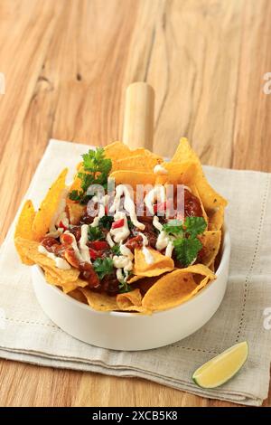 Yellow Nachos with Ground Beef, Cheese Cream Mayonaise,  and Salsa Sauce on White Bowl Stock Photo
