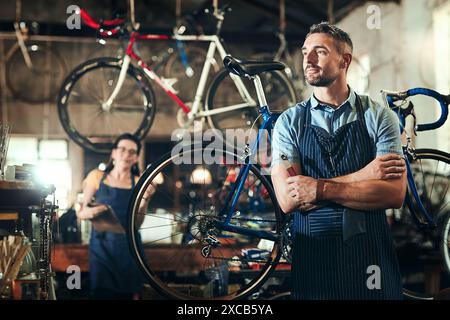 Mechanic, thinking and arms crossed at work in bicycle repair shop or maintenance garage. Bike, mature repairman and service with a professional Stock Photo